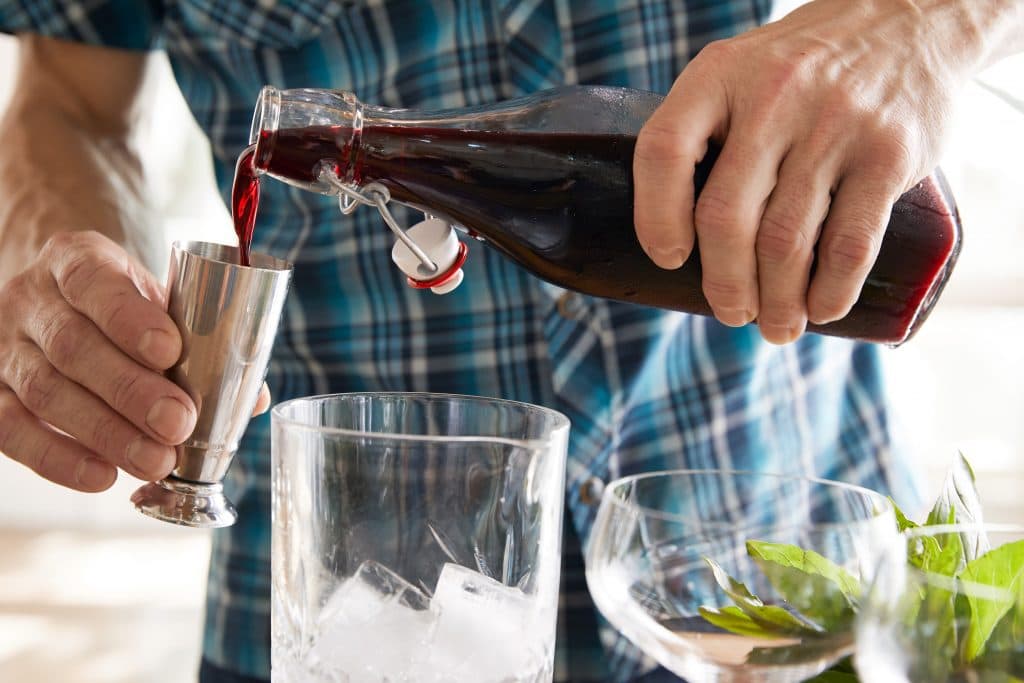 person pouring cocktail into a metal mixer