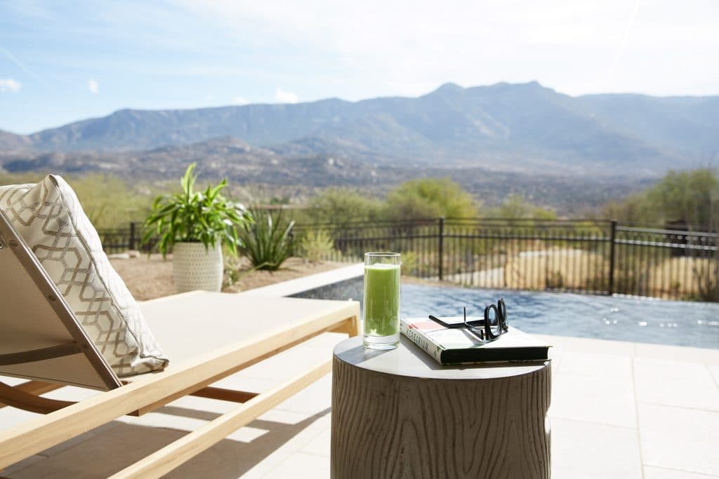 lounge chair, fresh juice and a book beside a pool with a view