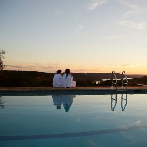 two people watching the sun set by the pool