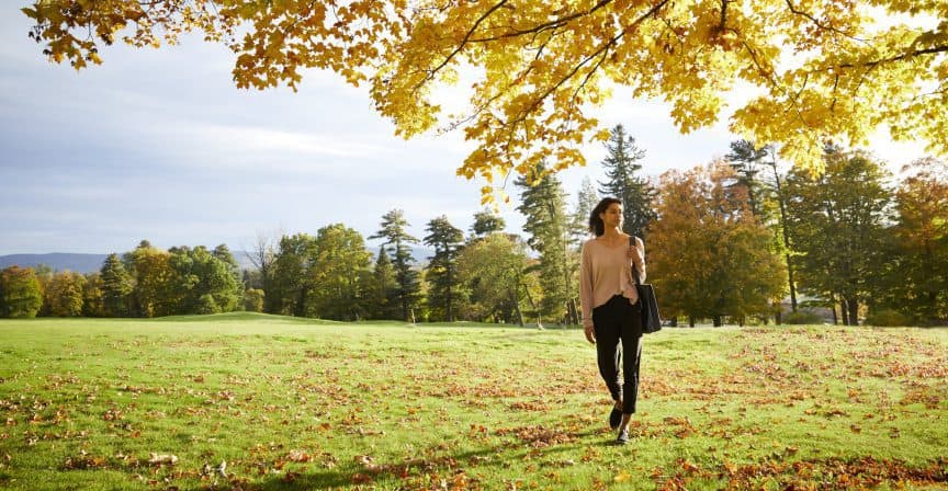 person walking on grass with fallen leaves