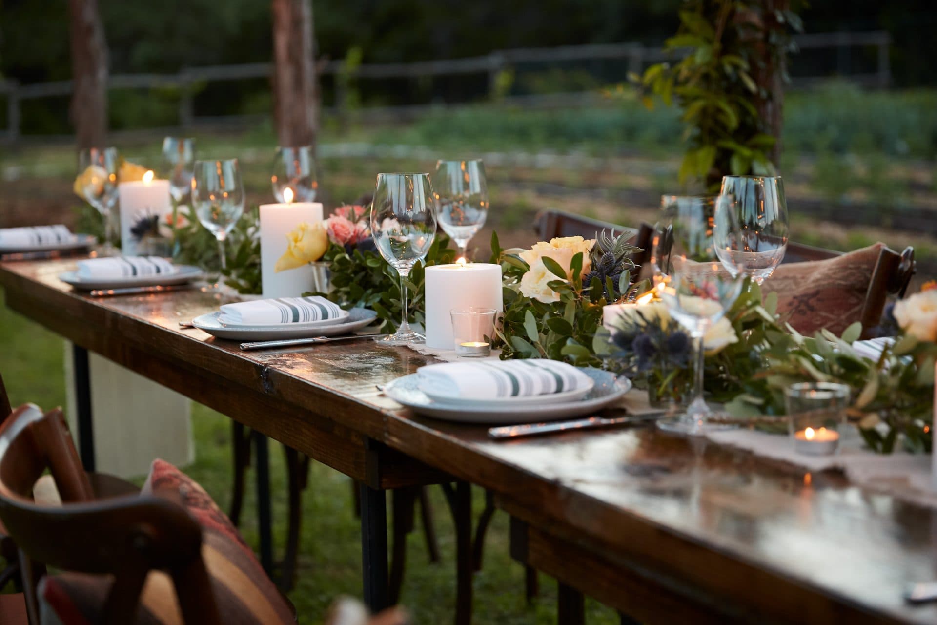 long wooden dinner table with floral and plating decorations